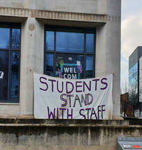 Banner with 'Students Stand With Staff' hanging from building